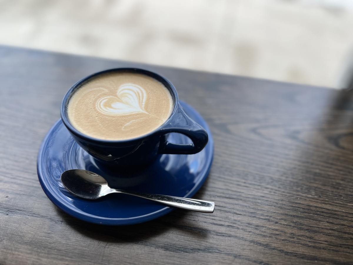 A blue cup of coffee with a heart design on top.